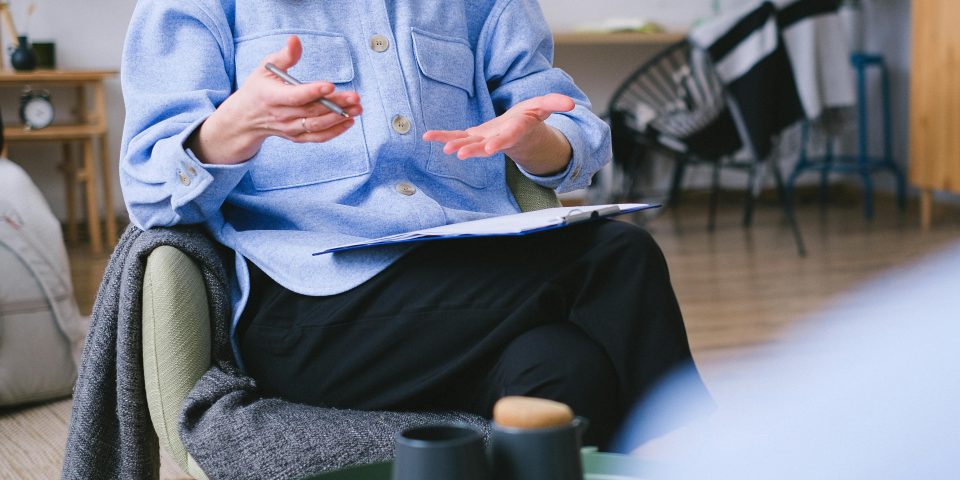 A therapist consults with a client in a contemporary office, focusing on mental health.